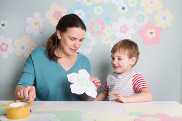 Child boy with mother have a fun cutting out scissors paper in the home. Preparation of a decor for Easter.  children's creativity..