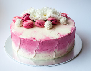 Wedding cake with white spring flowers and macaroon on top. Delicious pink cake isolated on white background.