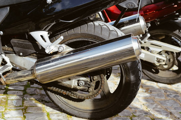 Back view closeup of motorcycle, chrome exhaust outdoors background