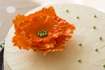 Top of cake with decorative balls and a big orange flower.