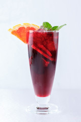 Red cocktail with orange, ice and mint