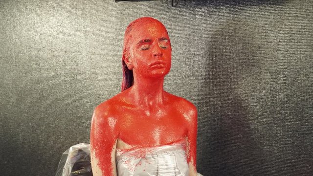 Girl covered in red paint sitting in the studio
