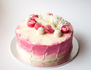 Wedding cake with white spring flowers and macaroon on top. Delicious pink cake isolated on white background.
