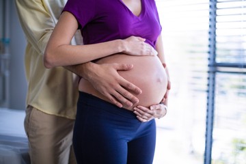 Mid section of man touching pregnant womans belly in ward