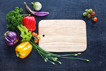 Fresh farm vegetables, knife on a dark background. Bell pepper, cherry tomatoes, eggplant, cucumber and greenery. Space for text.