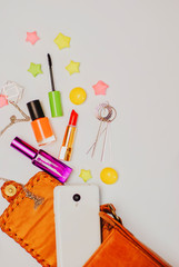 Fashion concept : Flat lay of orange leather woman bag open out with cosmetics, accessories and smartphone on white background