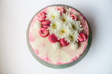 Obraz na płótnie Canvas Wedding cake with white spring flowers and macaroon on top. Delicious pink cake isolated on white background.