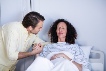 Man comforting pregnant woman during labor in ward