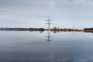 reflection of electricity pylon in water against sky 