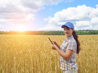 Naklejka na ściany i meble Young pretty farmer girl standing in yellow wheat field