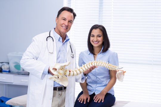 Portrait of physiotherapist and patient holding spine model