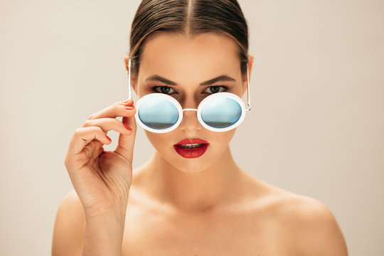 Fototapeta Fashion woman peeking over sunglasses