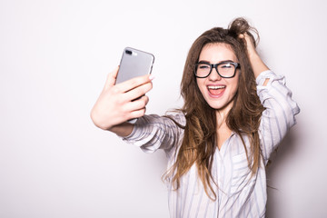 Portrait of a young attractive woman making selfie photo on smartphone isolated