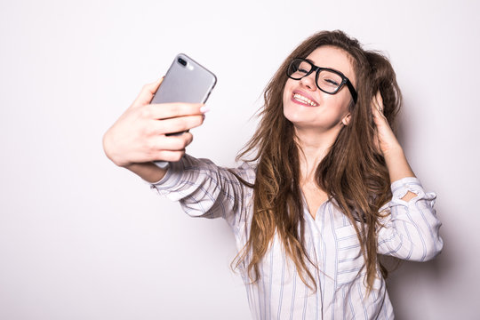 Portrait of a young attractive woman making selfie photo on smartphone isolated