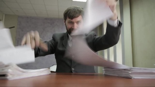 Businessman nervously signing and stamping incoming documents. office worker scatter documents around