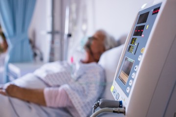Close-up of vital signs monitor with senior patient 