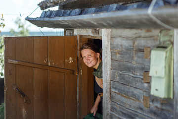 Smiling young suntanned woman with a rural door