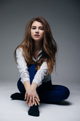 Beautiful woman sitting on the floor. Girl with long wavy hair.