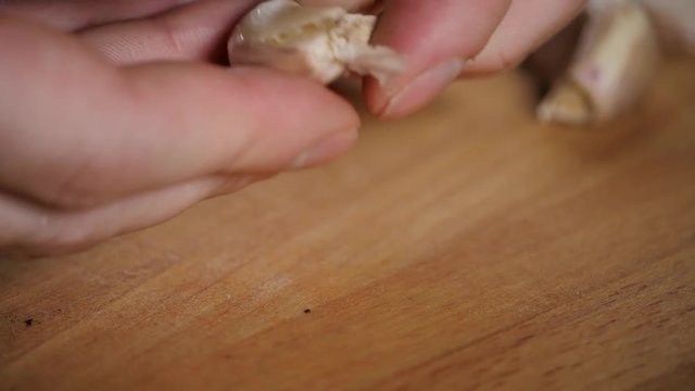 Close up cut garlic over wooden cutting board with knife, chile and pepper on background
