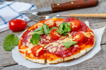 Homemade mini pizza with salami and tomatoes.