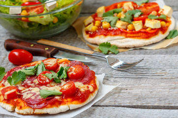 Homemade mini pizzas (meat and vegan) with vegetable salad.