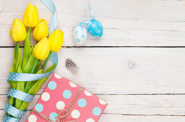 Easter background with blue and white eggs, yellow tulips and gift box