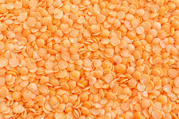 Red lentils. Background with texture of grains of lentils. Orange bright food background top view.