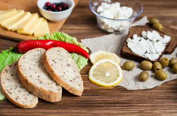 A sandwich with cheese and butter for breakfast, bread and pastries on the table. Wooden, dark background. Banner for a bakery.