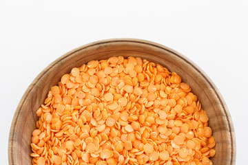 Red lentils in a pottery top view. Background with texture of grains of lentils. Orange bright food background top view.