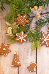 Gingerbread christmas cookies with green pine branch needles with bell and angel on wooden background