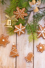 Gingerbread christmas cookies with green pine branch needles with bell and angel on wooden background