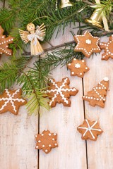 Fototapeta na wymiar Gingerbread christmas cookies with green pine branch needles with bell and angel on wooden background