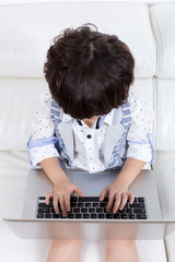 Asian Chinese little boy sitting on the couch with laptop