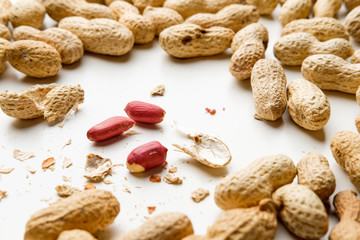 Cracked peanuts and peanuts in nutshell on white background