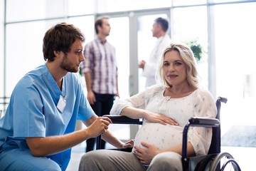 Obraz premium Male doctor talking to pregnant woman in wheelchair