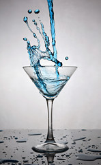 Splash in glass of a blue alcoholic cocktail drink