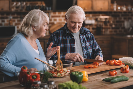 Portrait Of Smiling Senior Man And Woman Making Salad Together