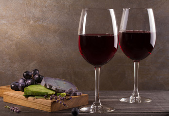 Glasses and bottle of red wine with grape, lavender and pesto cheese on chopping board. Wine and food still life