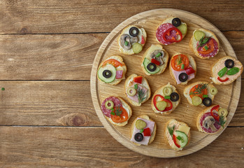 Delicious Crostini with different toppings on wooden background
