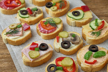 Delicious Crostini with different toppings on wooden background