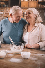 senior couple cooking pancakes on kitchen at home