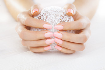 pink manicure with a white ball of yarn