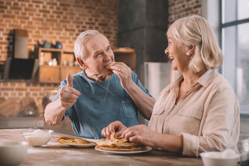 senior couple eating pancakes on kitchen at home