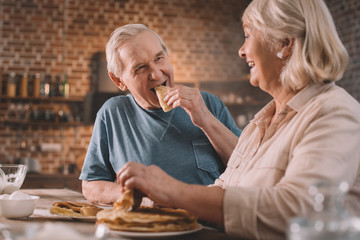senior couple eating pancakes on kitchen at home
