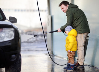 Middle age man and his little son washing a car on a carwash