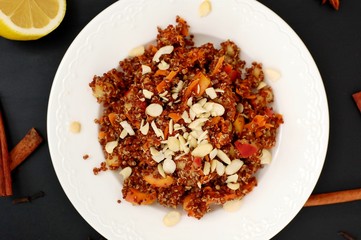 Salad with red quinoa,apple and carrot with almond on white plate on black background