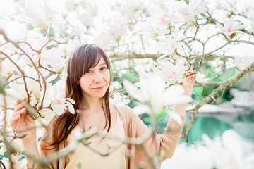 Obraz na płótnie Canvas Springtime background. Beautiful woman and white magnolia in park.