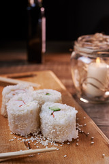 Japanese food, sushi roll with crab, sesame seeds, cucumber, cheese, on a wooden board