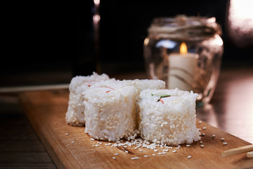 Japanese food, sushi roll with crab, sesame seeds, cucumber, cheese, on a wooden board
