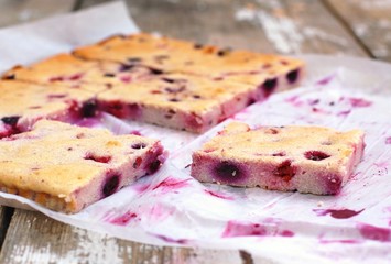 Gluten free cake with cottage cheese and forest fruits on paper on wooden background
